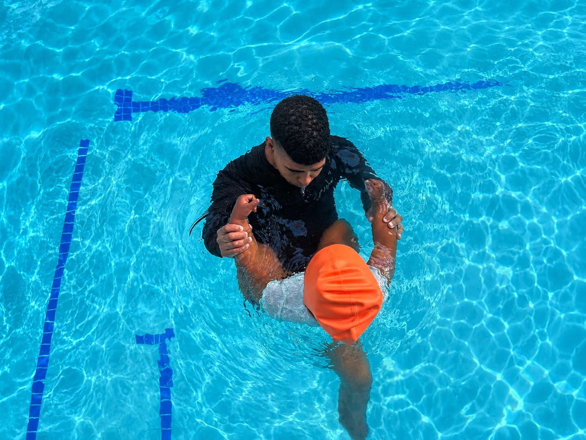 Instructor gently supporting a child in the water during a swimming lesson