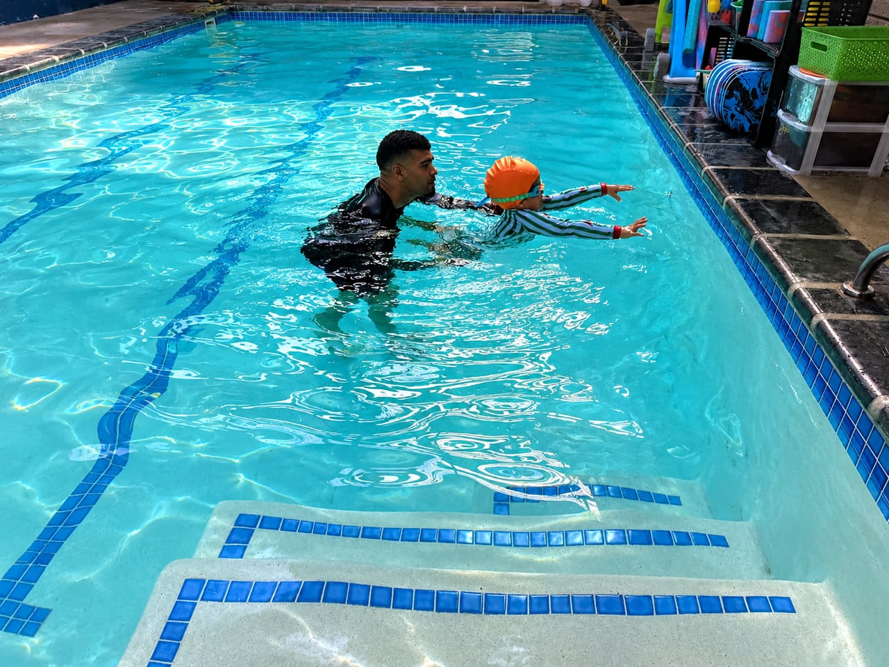 Instructor walking a young swimmer through a glide across the pool