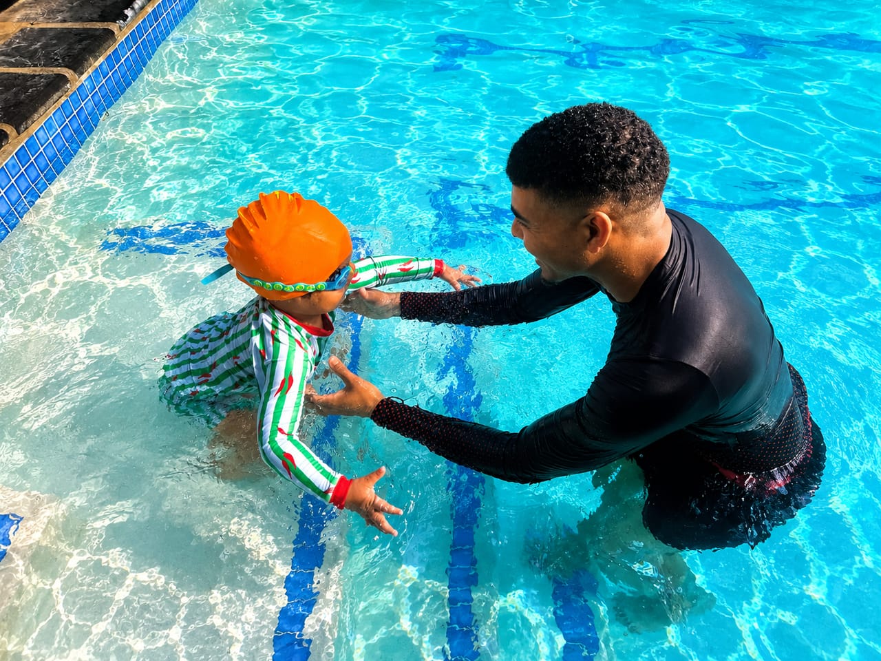 Instructor reassuring a small child at the pool steps during a lesson