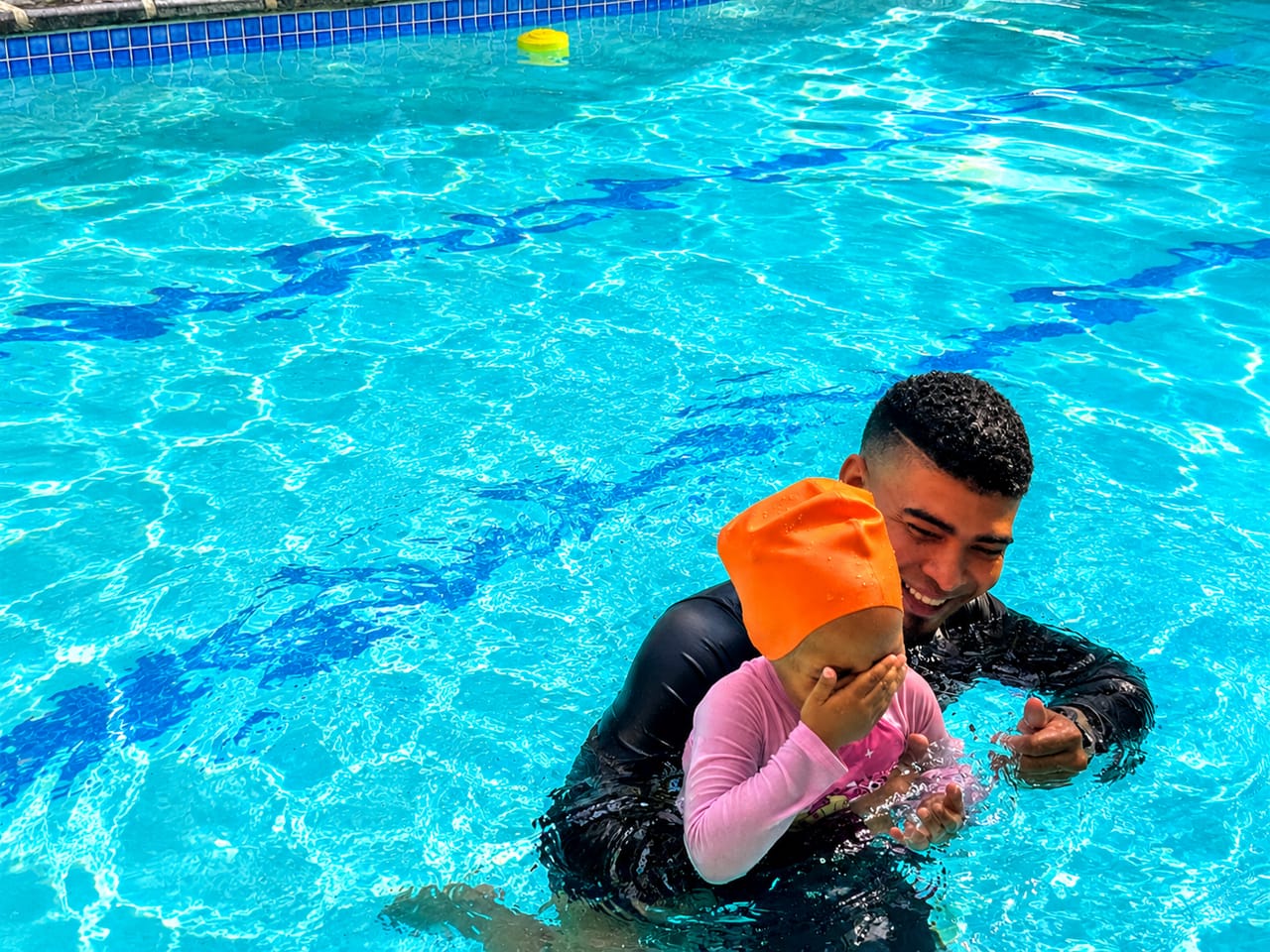 A smiling instructor holding a young child during a confidence-building session