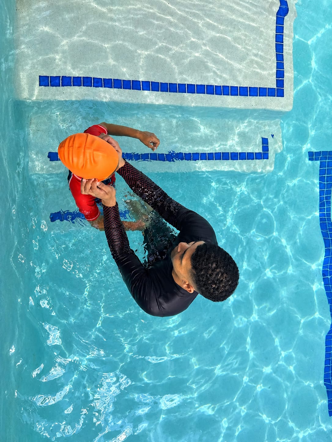 Overhead view of an instructor supporting a young child in the shallow end