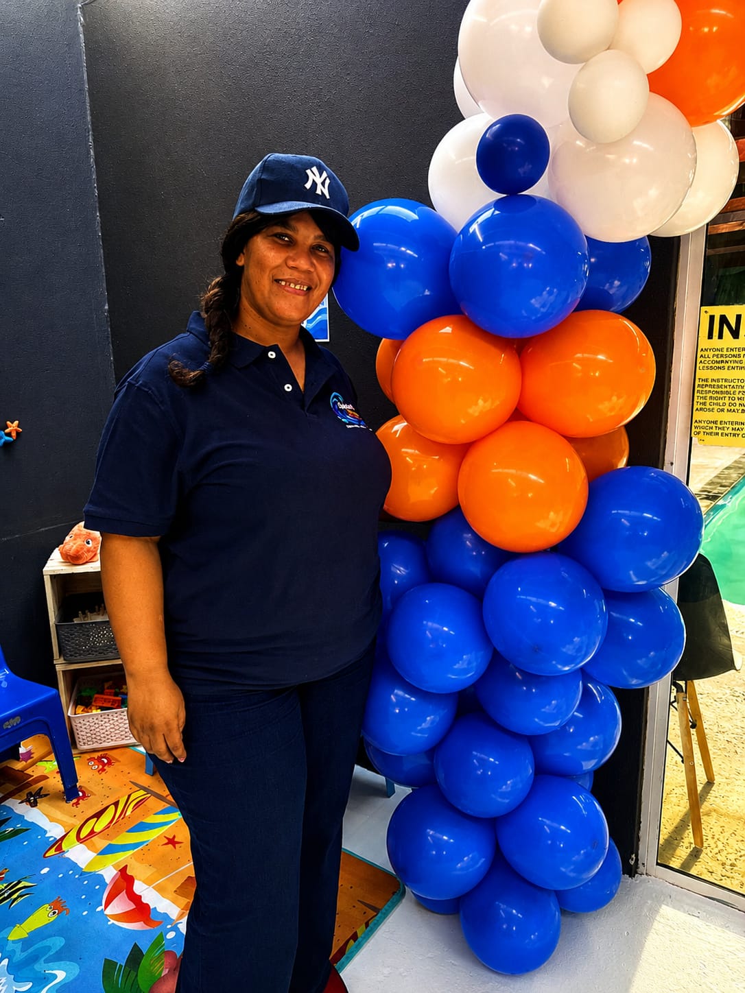 A Splash & Grow team member beside a tall balloon column in the children's play area at the open day