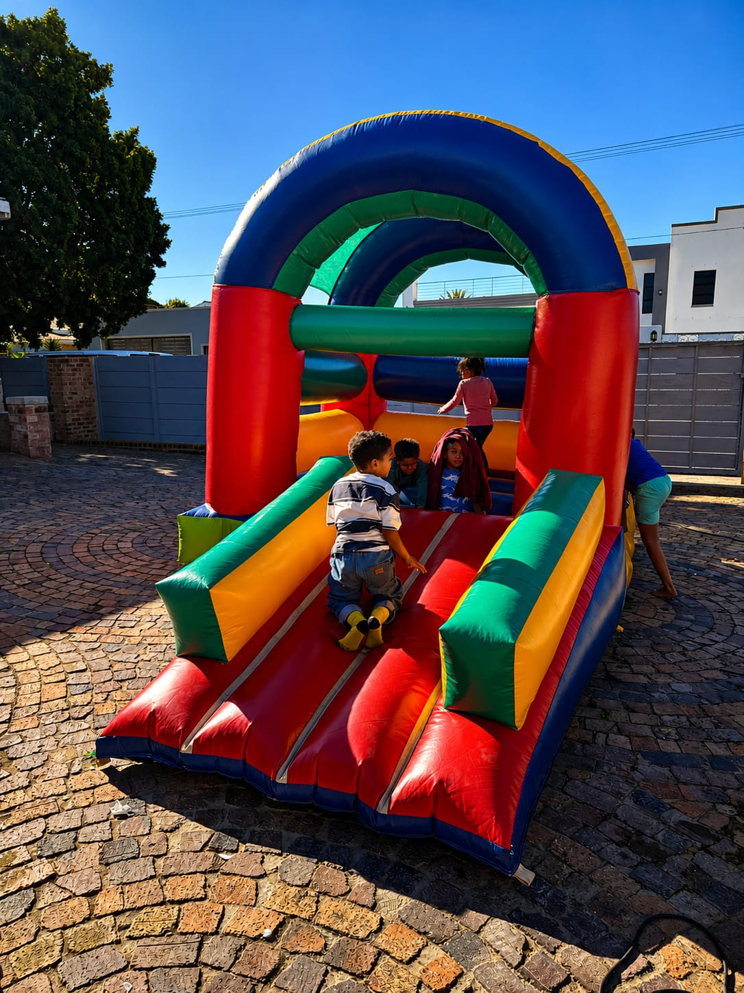 Children enjoying the inflatable bouncy castle outdoors under a clear sky at the open day